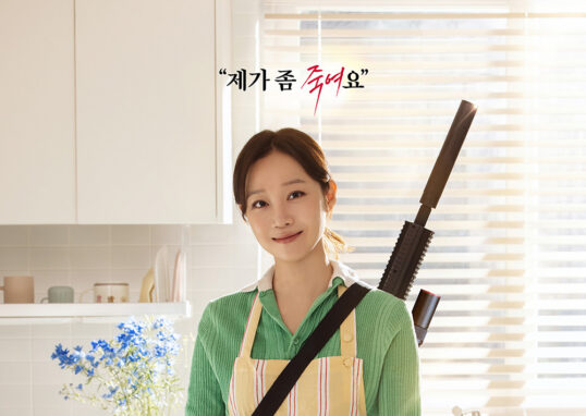 유부녀 킬러에서 앞치마를 두른 여성 인물이 주방에 서 있는 장면