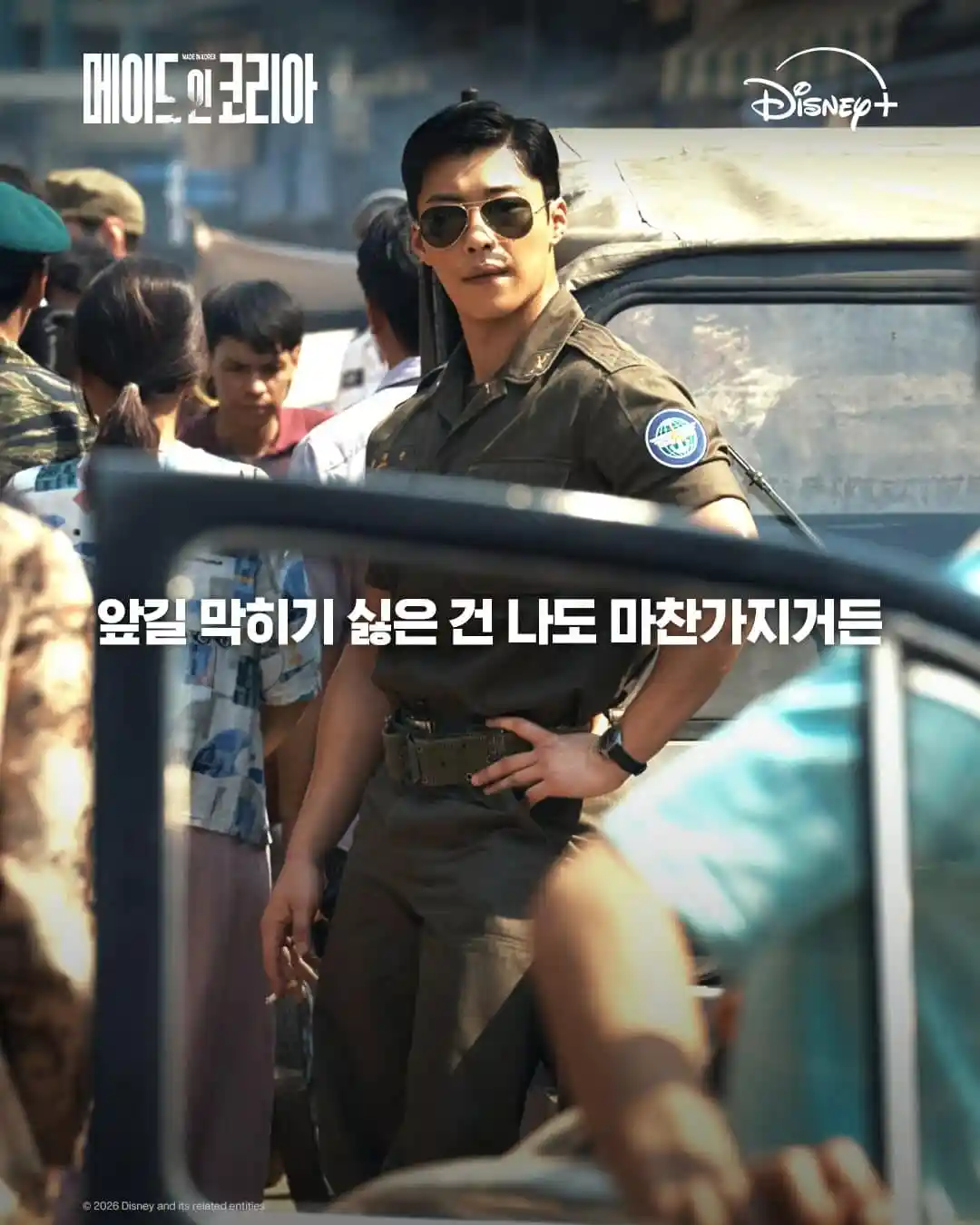 메이드 인 코리아 공식 명대사 이미지에서 군복 차림 인물이 군중 사이에 서 있는 1970년대 배경 장면